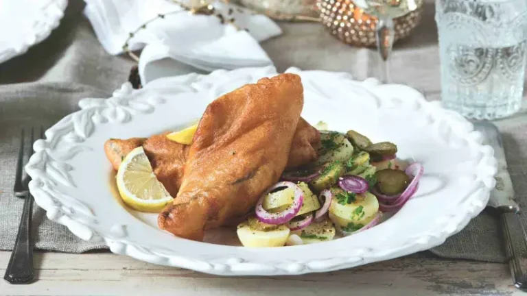 Smažená ryba a salát s brambory na elegantním bílém talíři