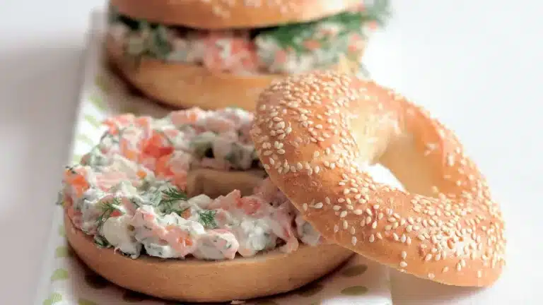 Čerstvý bagel s lososovou pomazánkou a koprem na talíři